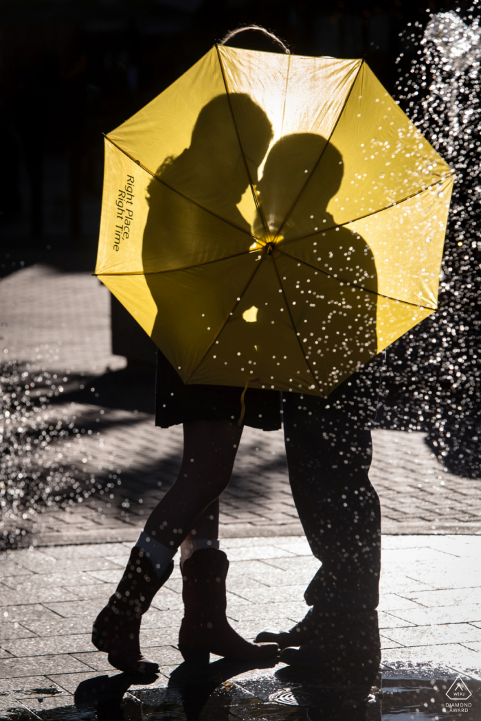 Fort Collins couple pre-wed Silhouette portrait behind umbrella with fountain in the foreground, inspired by TV show How I Met Your Mother