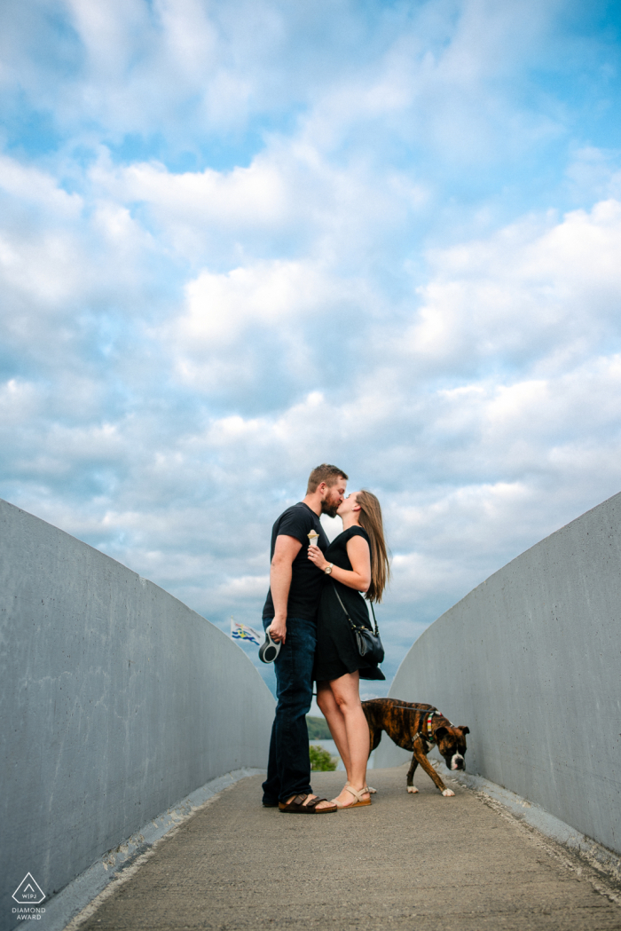 Westport Lookout Point Fine Art Ritratto pre matrimonio per la coppia dell'Ontario in piedi su un ponte a mangiare il gelato e portare a spasso il cane