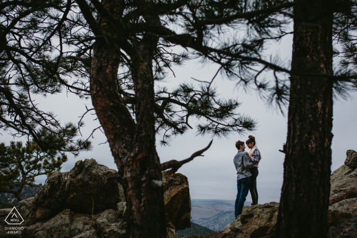 Boulder, CO Pre Wedding Photoshoot in a Fine Art Style for an Engaged couple embracing before a kiss through silhouetted pine trees Boulder, CO Pre Wedding Photoshoot in a Fine Art Style for an Engaged couple embracing before a kiss through silhouetted pine trees