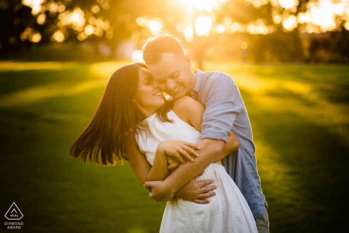 Perth Fine Art Engagement Image showing A beautiful hug on the green grass with warm sunlight