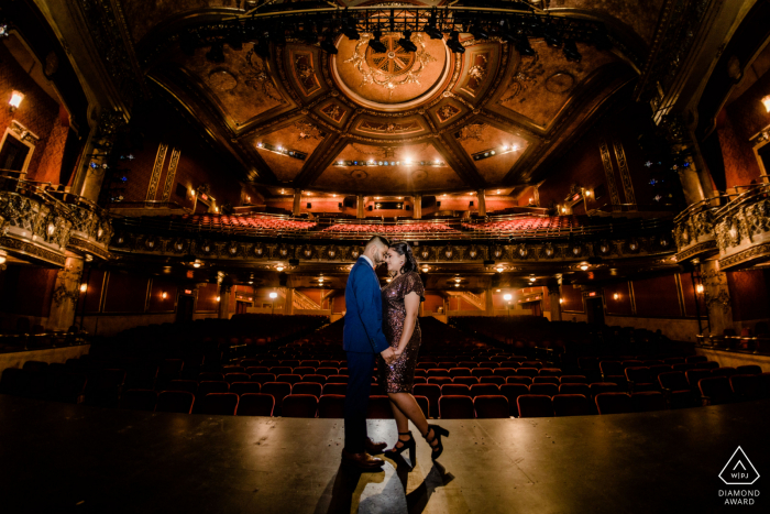 Toronto Artful Engagement Picture at a theater as the couple stand on the stage in formal clothes Toronto Artful Engagement Picture at a theater as the couple stand on the stage in formal clothes