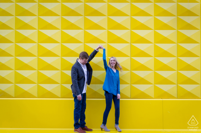 Sessão de noivado de belas artes em Denver para um casal dançando em frente a uma parede colorida no centro da cidade