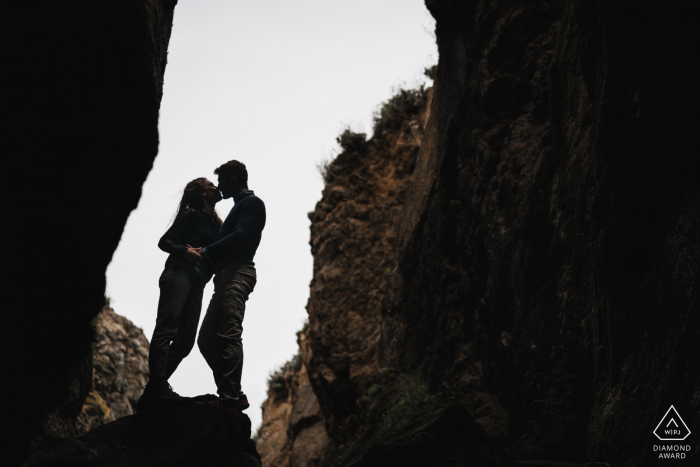 Saint Cast, France Fine Art Pre Wedding Portrait of The couple framed in the opening of the rocks and cliffs Saint Cast, France Fine Art Pre Wedding Portrait of The couple framed in the opening of the rocks and cliffs