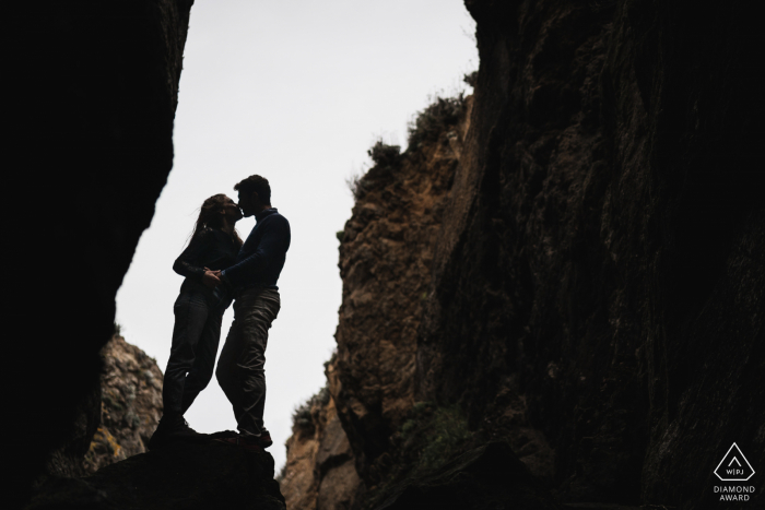 Saint Cast, France Fine Art Pre Wedding Portrait of The couple framed in the opening of the rocks and cliffs