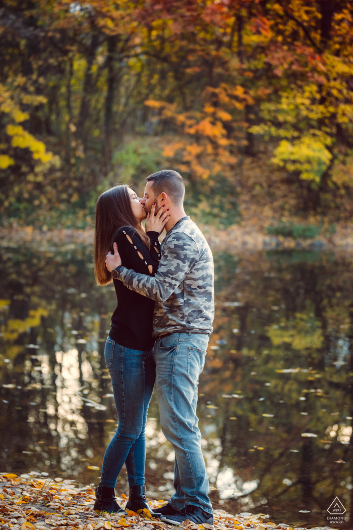 See des Südparks, Sofia Fine Art Pre Wedding Porträt des Paares, das sich am Wasser unter den Herbstblättern küsst