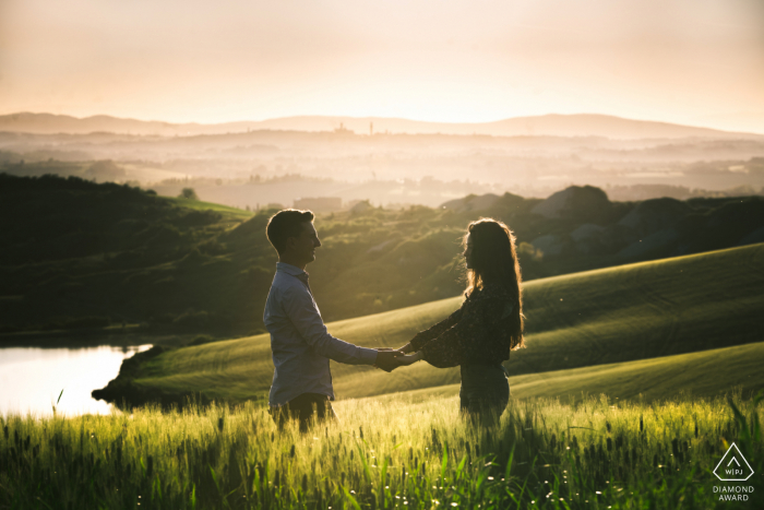 Photo by: <a href="https://www.wpja.com/photos/diamond-award-top-wedding-engagement-photographer/2622391">Alessia Bruchi - Siena Siena Crete Senesi, Siena portrait e-session of a couple holding hands with the hills and valleys as a backdrop