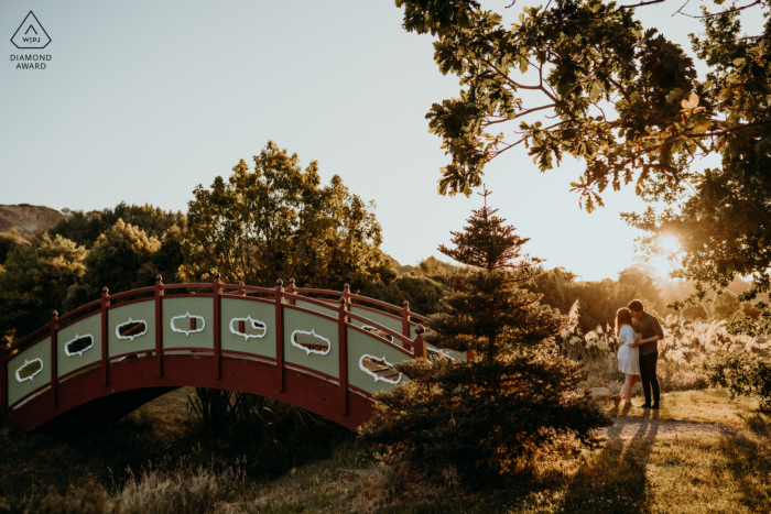 Halsweh Quarry Park Christchurch Vor-Ort-Portrait-E-Shooting eines Paares, das sich bei Sonnenuntergang an einer Brücke küsst