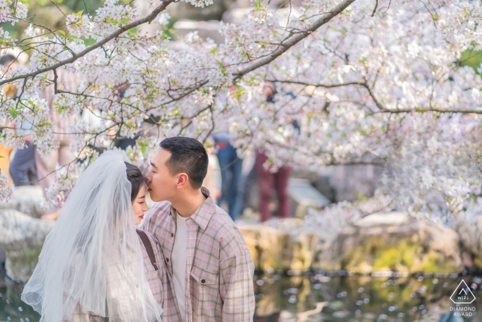 Photo by: <a href="https://www.wpja.com/photos/diamond-award-top-wedding-engagement-photographer/2622535">Chenjie Tan - JiaXing China environmental engagement e-session with trees and white flowers