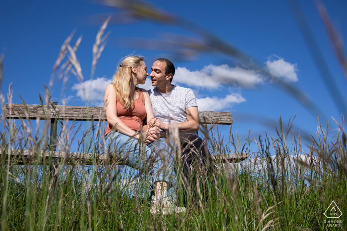 e-shoot de portrait sur place de la Colline de Sion pour un couple assis sur un banc de ferme rustique dans les hautes herbes rurales