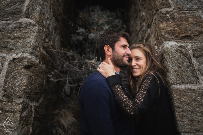 Sessão eletrônica de engajamento ambiental em Saint Cast, França com um casal em tons escuros em uma enseada de construção de pedra