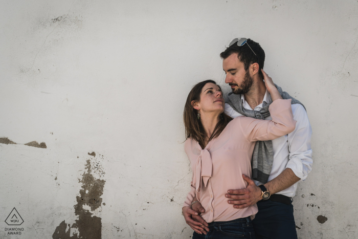 Île d'Yeu, France e-session portrait avec le couple embrassé contre un mur peint en blanc