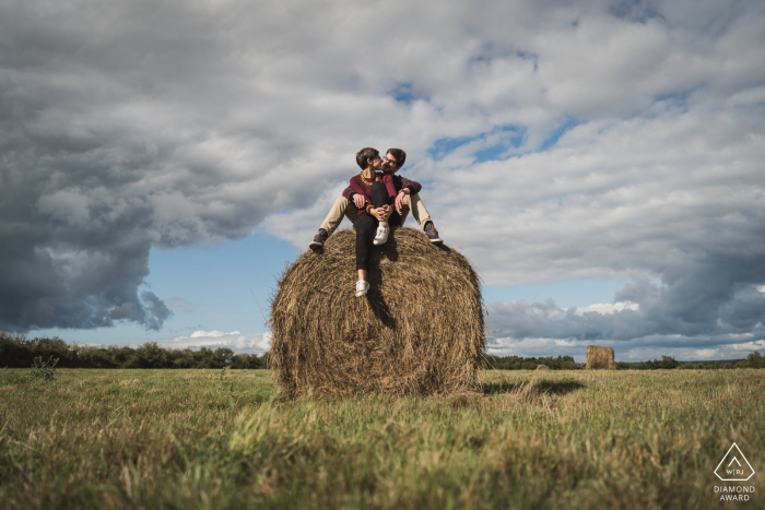 Gulf du Morbihan, France environmental engagement e-session with the young couple sitting on a large round hay bale in the open field