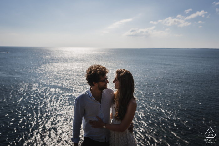 Crozon, France portrait e-session with The couple high above the water created while shooting toward the sun