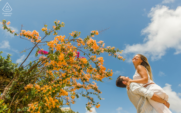 Maceió, Alagoas environmental engagement e-session with a man holding his future bride in his lap and she smiles