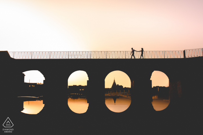 True Love Engagement Portrait Session in Siracusa displaying a couple walking over the bridge during sunset at Spring in Sicily