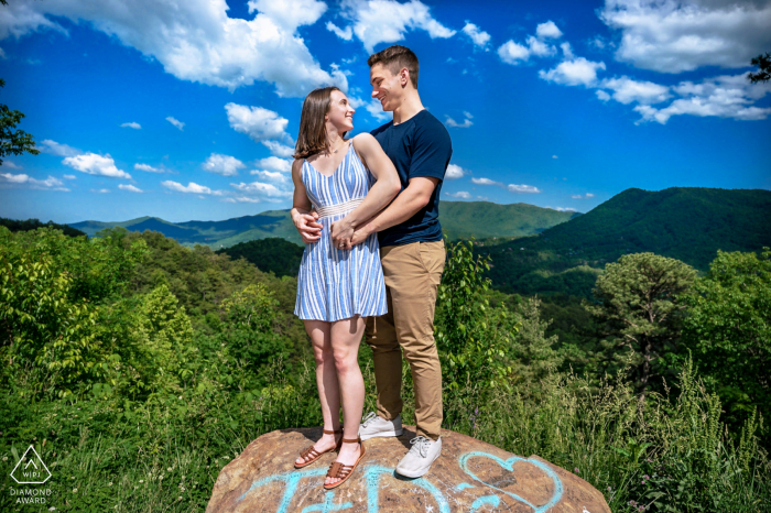 True Love Engagement Portrait Session at the Foothills Parkway displaying a TN couple kisses on a rail next to the road as a car drives by TN True Love Engagement Picture Session in Foothills Parkway showing a couple standing on a rock at one of the parkways overlooks