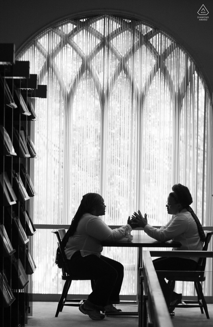 Porträtsitzung „True Love Engagement“ in der Emory Library in Atlanta, die ein Paar am Tisch in der Theologiebibliothek zeigt, wo sie sich trafen