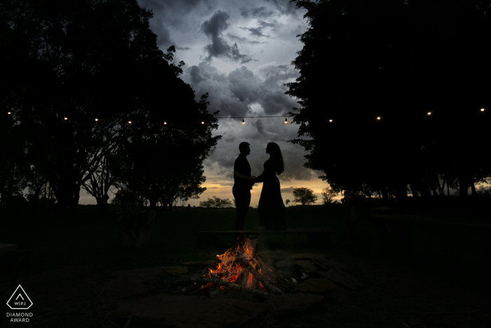 True Love Pre-Wedding Portrait Session at Fazenda Água Limpa in Hidrolândia  capturing a GO couple holding each other below the sunset clouds