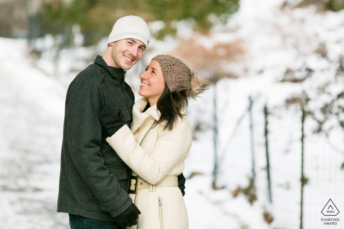 Sesión electrónica de pareja de Carl Schurz Park en Nueva York, manteniéndose caliente compartiendo el calor corporal en un día de nieve