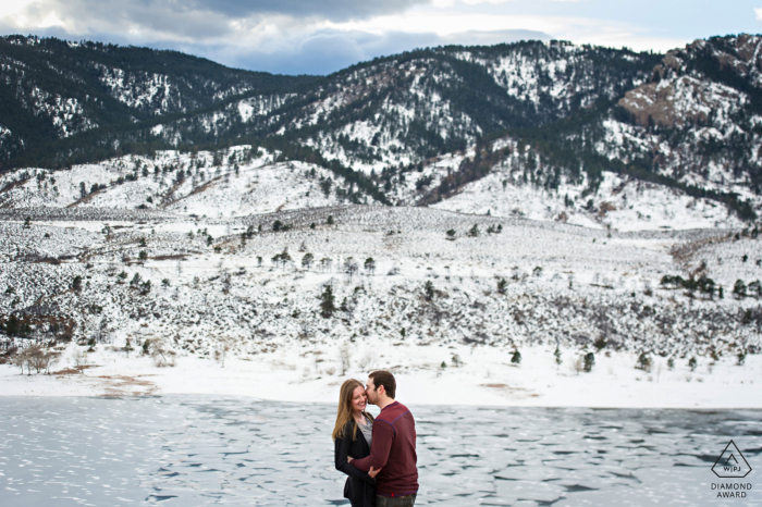 Fort Collins, Colorado, pareja e-shoot en Horsetooth Reservoir mientras está de pie mirando los témpanos de hielo debajo