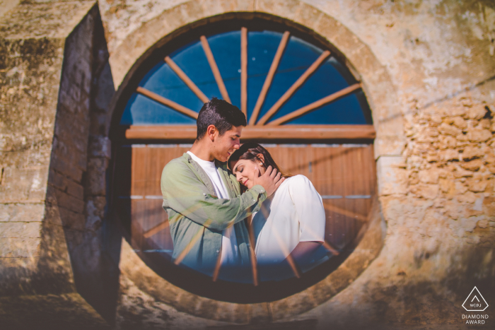 Casal de Marzamemi e-shoot em uma janela emoldurando a imagem com amor na Sicília