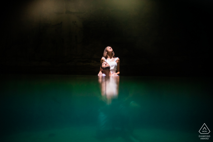 Sessão eletrônica do casal Cenote Suytun Yucatan enquanto olha para a luz que vem de cima