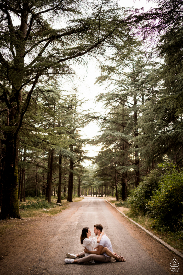 Luberon couple e-shoot sitting in the roadway below the tall forest trees