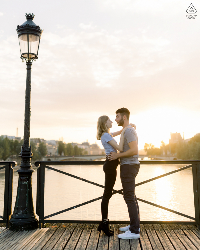 Pont des Arts, Paris couple e-session while embracing next to a Parisian lamppost at sunset