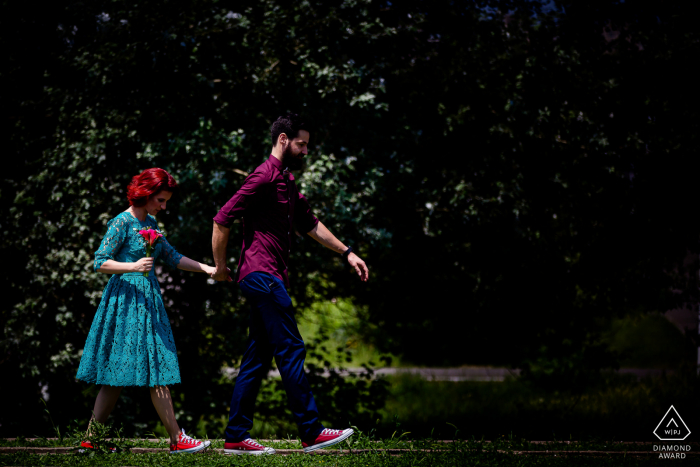 Bukarest Braut und Bräutigam, die für ein Foto vor der Hochzeit modeln, während sie mit ihren Blumen im Park spazieren gehen