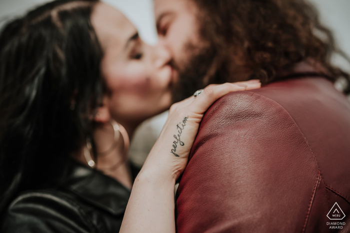 Zollverein Coal Mine Industrial Complex engagement shoot with a couple kissing, focus is on the "perfection" tattoo of the hand of the woman