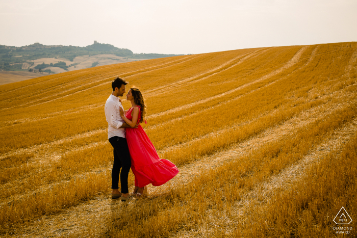 Los futuros novios de Val d'orcia, posando para una sesión de fotos de compromiso antes de la boda en la campiña italiana en medio del campo de trigo