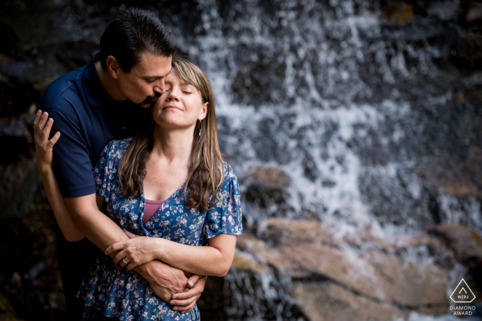 Maxwell Falls, Colorado, sessione di immagini ambientali pre-matrimonio con la coppia che si abbraccia vicino a una cascata