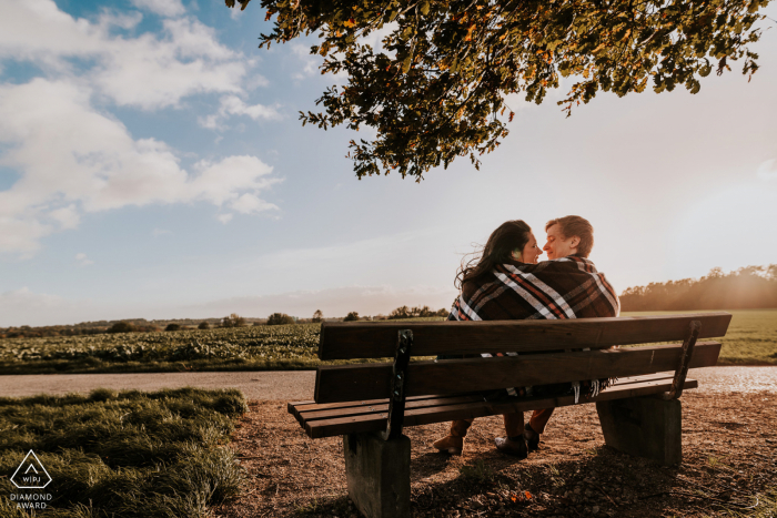 Mülheim an der Ruhr, Alemanha, do lado de fora da sessão fotográfica ambiental antes do casamento, enquanto o casal se aconchega no banco