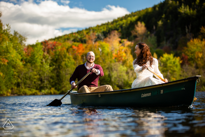 Adirondack Park, New York, Umweltpaar vor der Hochzeitsfotosession, als sie auf ihn zurückblickt, als sie im Herbst über den See paddeln