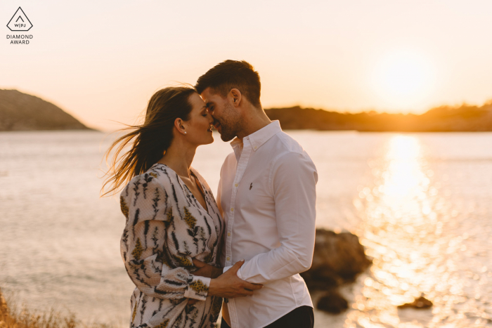 Santorini environmental pre wedding image session with a romantic couple kissing in golden hour