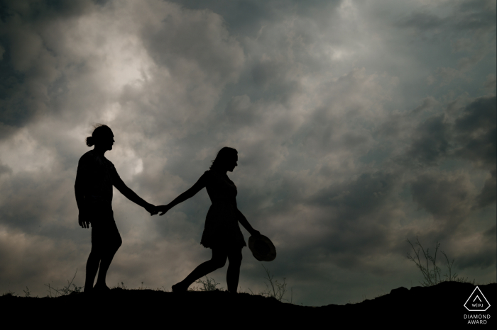 Sur place Perpignan couple shooting portrait de fiançailles marchant sur les collines sous les nuages ​​du crépuscule