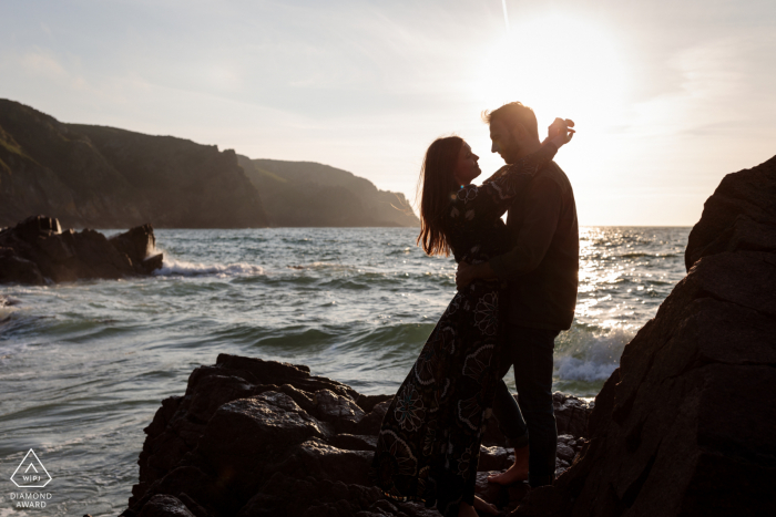 On location Plemont Bay, Jersey CI couple engagement portrait shoot on the rocks by the sea at sunset