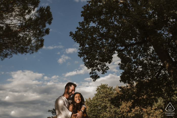 Villa Petrea, Toskana, lebenslustiges Paar modelt für eine Pre-Wedding-Session unter den Bäumen Italiens