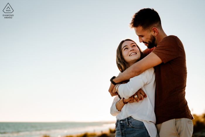 Ein französischer Hochzeits-, Elopement- und Verlobungsfotograf hat dieses süße Porträt dieses Paares aus Montpellier erstellt, das sich am Meer umarmt