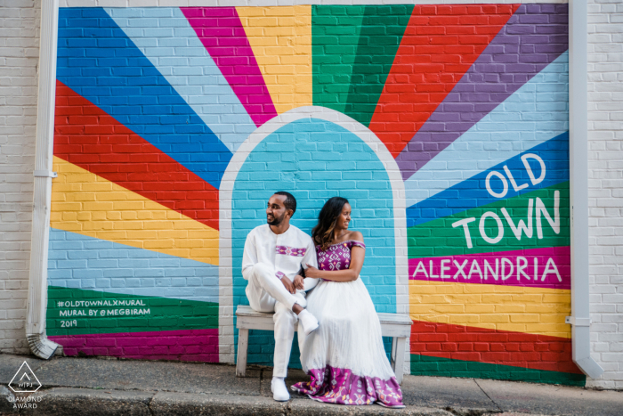 Um fotógrafo de casamento, fuga e noivado da Virgínia criou este retrato artístico e aventureiro deste casal VA sentado em uma praia com um mural de arte na parede atrás do tema Old Town Alexandria