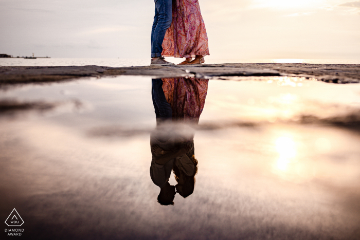 Ein italienischer Hochzeits-, Elopement- und Verlobungsfotograf hat dieses künstlerische Porträt dieses Triester Paares erstellt, das in einem Wasserbecken posiert und sich spiegelt