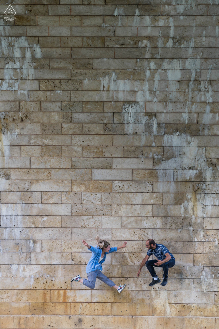 A France Wedding, Elopement, and Engagement Photographer created this fun, urban portrait of this Nerac couple having a sense of humor and jumping with excitement 