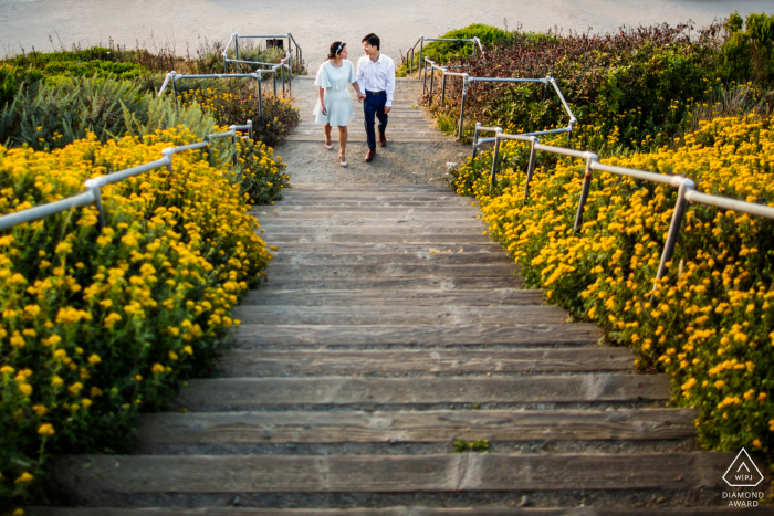 Un fotografo di matrimonio, fuga e fidanzamento in California ha creato questo ritratto artistico e avventuroso di questa coppia di San Francisco che cammina al piano di sopra circondata da fiori e dalla spiaggia