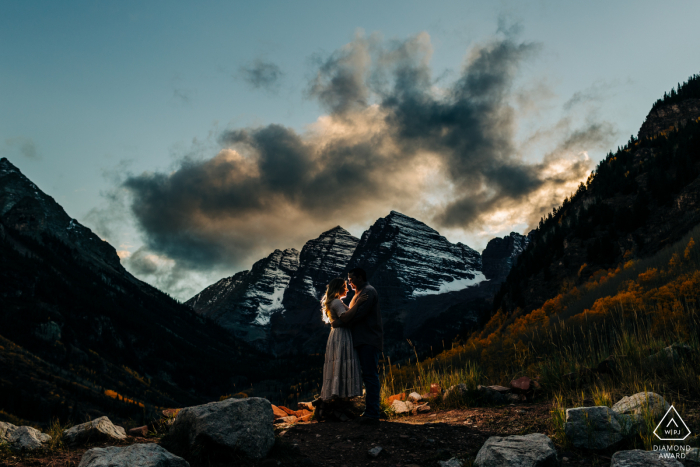 Un photographe de mariage, de fugue et de fiançailles dans les montagnes Rocheuses a créé ce portrait créatif et majestueux de ce couple du Colorado à Maroon Bells les représentant en contre-jour dans les montagnes au crépuscule