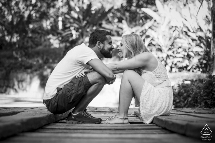 Um fotógrafo de casamento, fuga e noivado de Nova Friburgo criou este retrato criativo em preto e branco desse casal brasileiro sentado em uma madeira