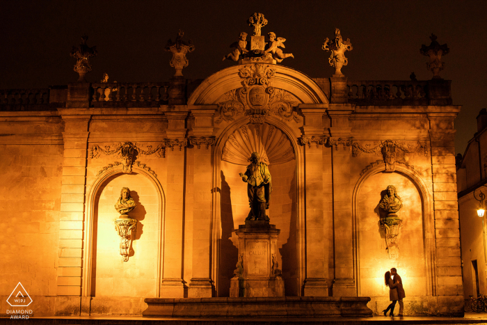 A France Wedding, Elopement, and Engagement Photographer created this artistic, urban portrait of this Nancy couple illustrating them kissing in front of statues at night