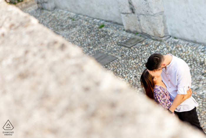 Ein Lovere-Paar posiert in der Lombardei, Italien, während einer Lifestyle-Porträtfotografie am Iseosee in einer schmalen Straße und von oben betrachtet