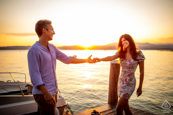 Séance de portrait de style de vie Sirmione au lac de Garde en Lombardie, Italie pour un couple au coucher du soleil sur le quai du bateau en bois à l'eau