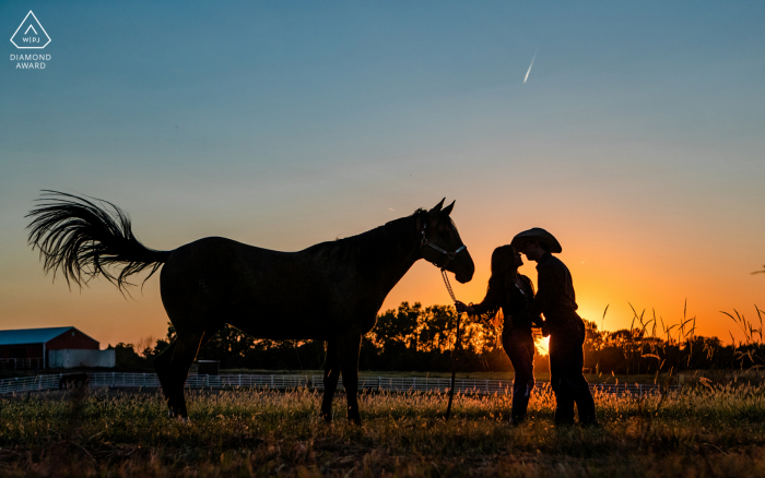 Nebraska lifestyle portraits session showing the Silhouette of a couple kissing with horse at sunset