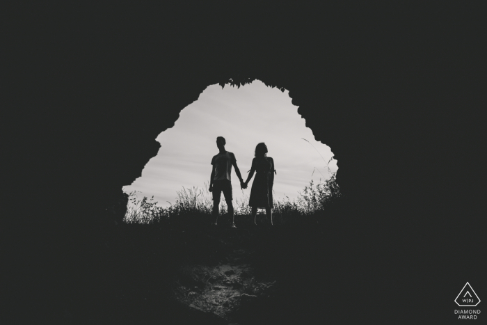Photographie de portrait lifestyle Mousson pour un couple de Meurthe-et-Moselle fiancé et posant en se tenant la main dans une ouverture de grotte Photographie de portrait lifestyle Mousson pour un couple de Meurthe-et-Moselle fiancé et posant en se tenant la main dans une ouverture de grotte